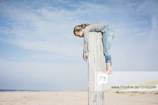 Little girl on the beach hanging on a pole