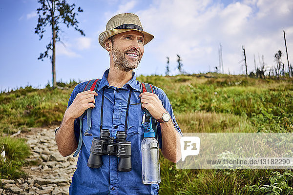 Smiling man with binoculars hiking in the mountains