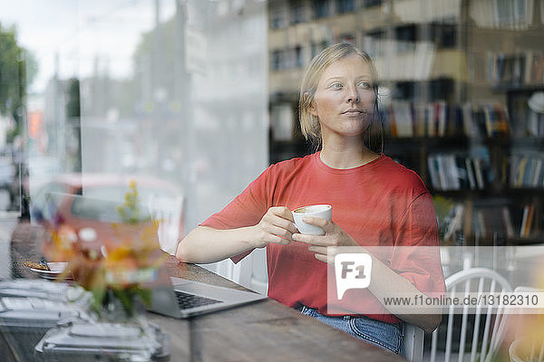 Young woman with laptop and coffee cup in a cafe