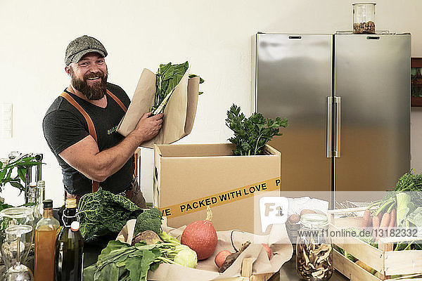 Reifer Mann mit Lieferservice verpackt Bio-Gemüse in Karton