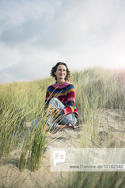 Mature woman relaxing on the beach  sitting in the dunes