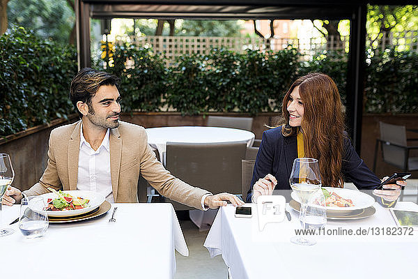Smiling woman and man with cell phone in a restaurant