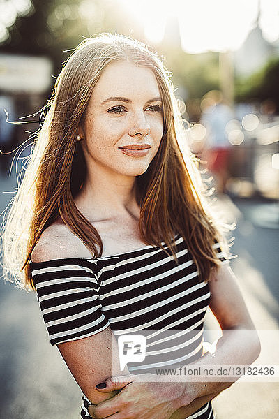 Portrait of smiling young woman wearing striped dress at sunset