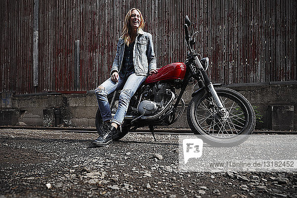 Lachende junge Frau mit Motorrad