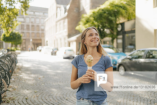 Niederlande  Maastricht  lächelnde blonde junge Frau mit Eiswaffel in der Hand in der Stadt