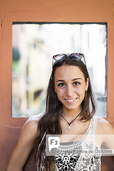 Porträt einer lächelnden jungen Frau mit braunen Haaren und Augen