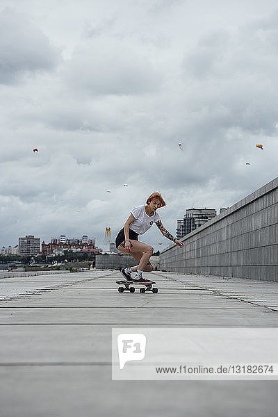 Junge Frau fährt Carver-Skateboard auf einer Promenade