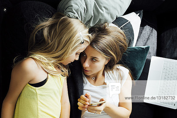 Entspannte Mutter und Tochter mit Handy auf dem Sofa