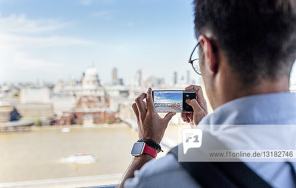 UK  London  Mann  der die Stadt von der Dachterrasse aus fotografiert