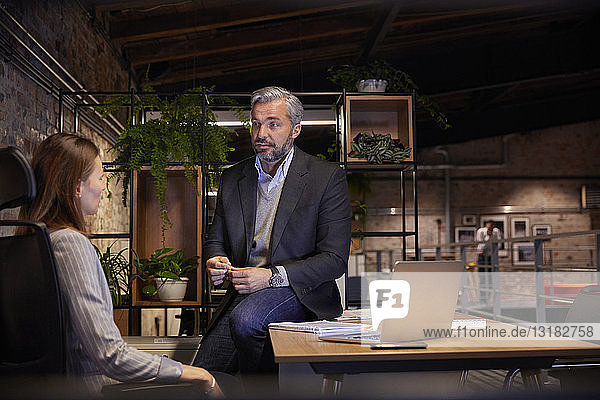 Geschäftsmann und -frau sitzen in einem modernen Büro und reden miteinander
