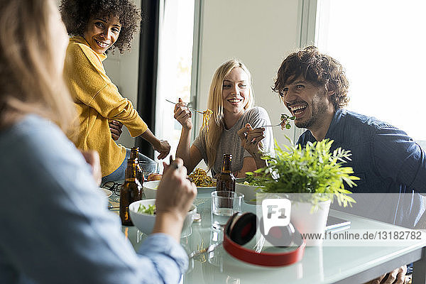 Freunde sitzen am Tisch  unterhalten sich  essen und trinken Bier