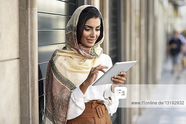 Spain  Granada  young muslim woman wearing hijab using tablet outdoor