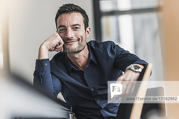 Mature man sitting in office  thinking  leaning head on hand