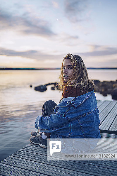 Junge Frau sitzt am Inari-See und schaut in die Kamera  Finnland