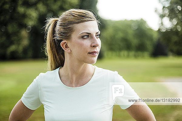 Porträt einer sportlichen jungen Frau in einem Park mit Blick zur Seite