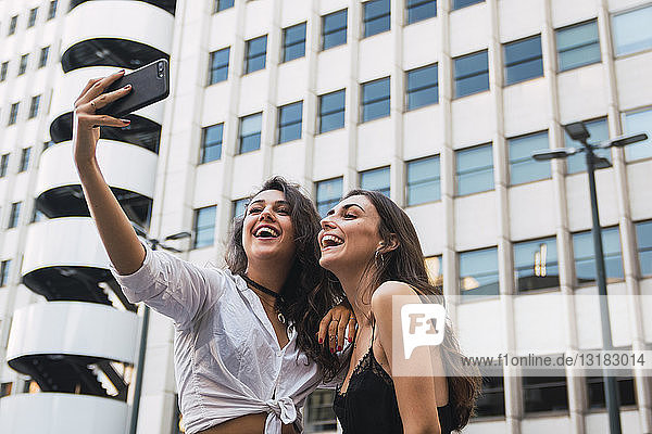 Laughing friends taking selfie with cell phone