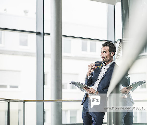Businessman standing in office building  using digital tablet