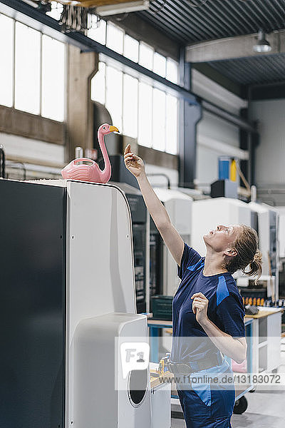Young woman working as a skilled worker in a high tech company  playing with a pink flamingo