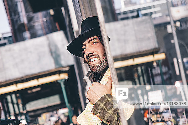 USA  New York City  Porträt eines bärtigen Mannes mit Skateboard und schwarzem Hut