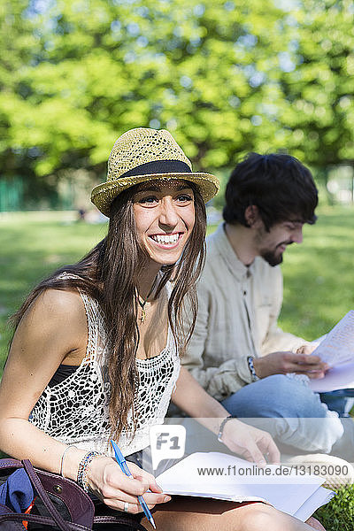 Portrait of happy young student sitting in the park