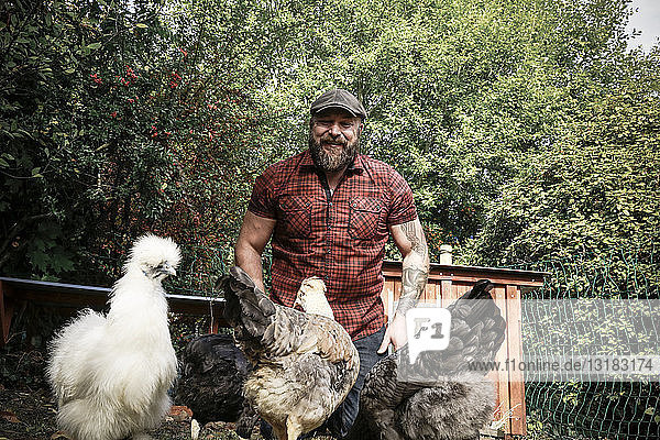 Mann im eigenen Garten  freilaufende Hühner