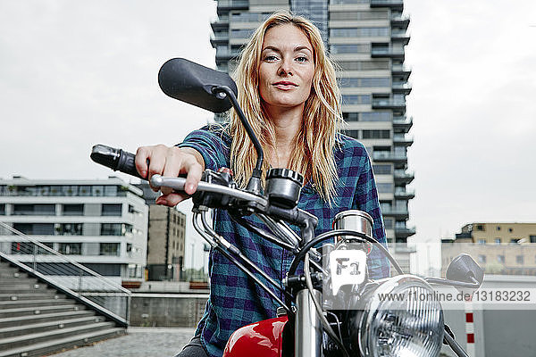 Porträt einer selbstbewussten jungen Frau auf Motorrad