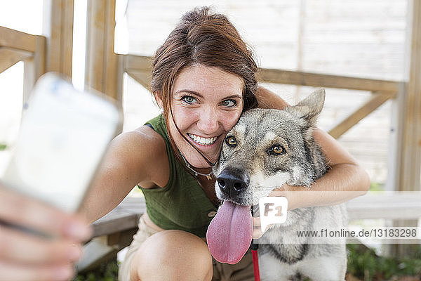 Junge Frau nimmt Selfie mit ihrem Hund mit Smartphone