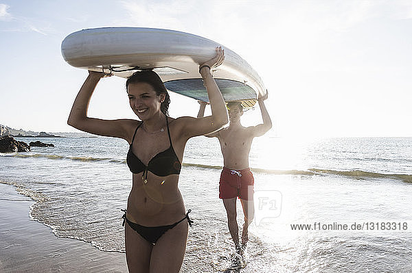 Frankreich  Bretagne  glückliches junges Paar mit einem SUP-Board gemeinsam auf dem Meer