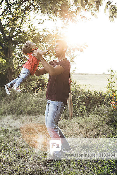Glücklicher Vater spielt mit Tochter auf der Wiese