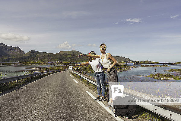 Junge Frauen trampen auf einer leeren Straße  Lappland  Norwegen