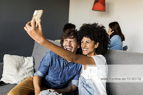 Happy couple sitting on couch taking a selfie
