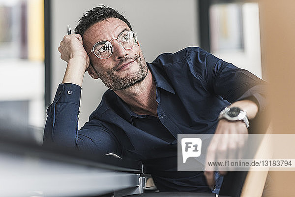 Mature man sitting in office  thinking  leaning head on hand