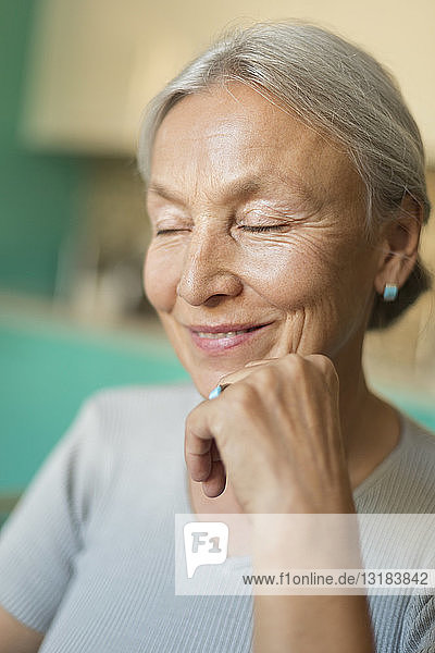 Porträt einer lächelnden älteren Frau mit geschlossenen Augen