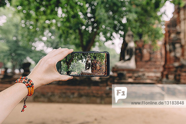 Thailand  Ayutthaya  Frau beim Fotografieren einer Buddhastatue im Wat Mahathat