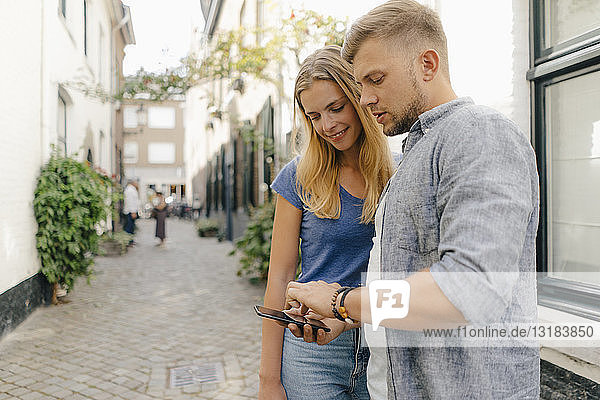 Netherlands  Maastricht  young couple looking at cell phone the city