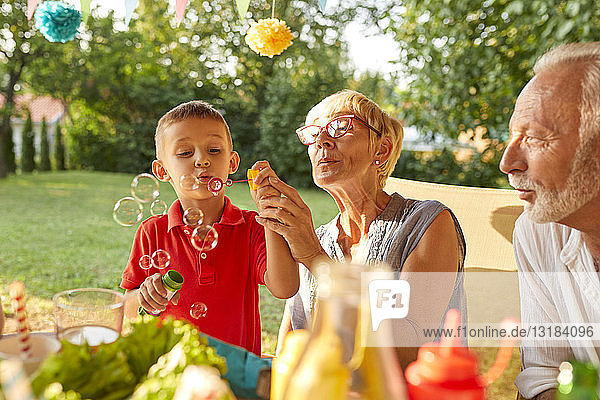 Großmutter und Enkel blasen Seifenblasen auf einer Gartenparty