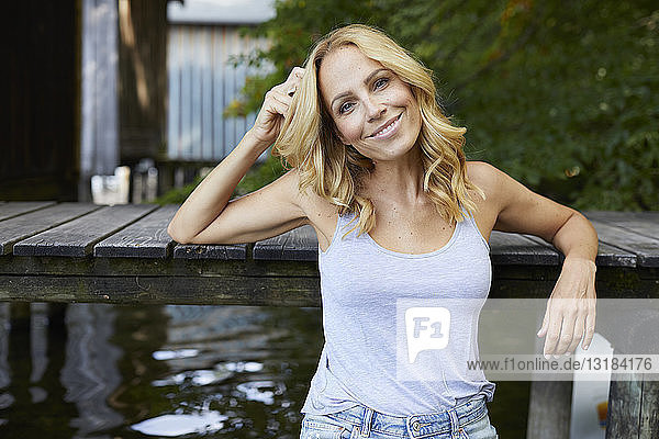 Lächelnde entspannte Frau am Holzsteg eines Sees