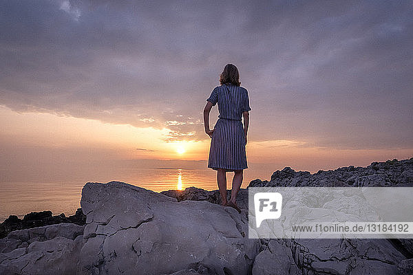 Kroatien  Istrien  Losinj  Frau steht bei Sonnenuntergang an Felsküste
