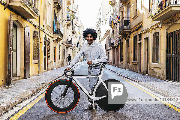 Mann steht auf einer Straße und zeigt sein Fahrrad
