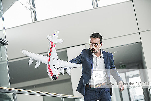 Geschäftsmann spielt mit Spielzeugflugzeug im Bürogebäude