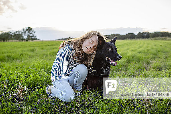 Mädchen mit einem Hund auf einem Feld sitzend