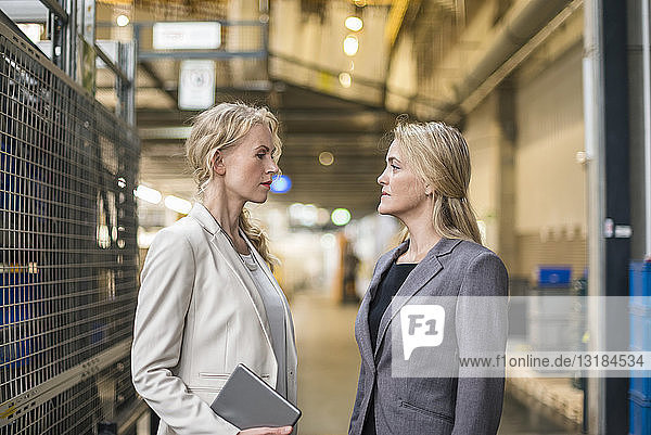Zwei Frauen stehen sich im Fabriklager gegenüber