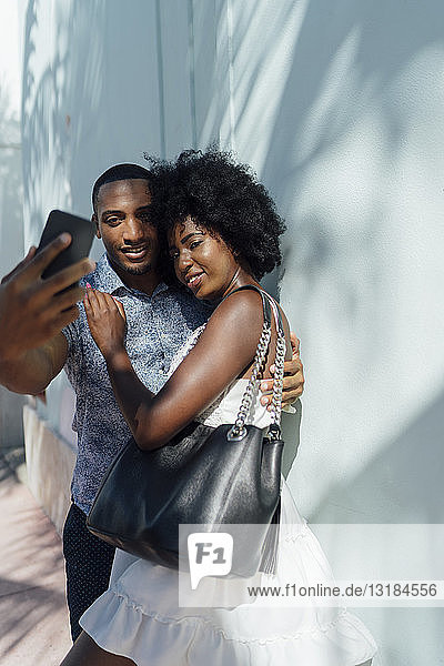 Lächelndes junges Paar  das sich umarmt und ein Selfie nimmt