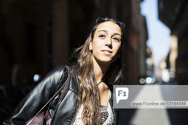 Porträt einer lächelnden jungen Frau in der Stadt  die in die Ferne schaut