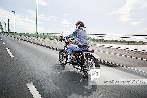 Junge Frau fährt Motorrad auf der Brücke