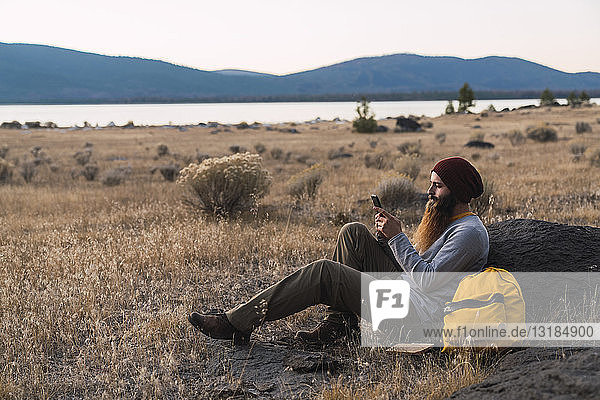 USA  North California  bearded young man using cell phone during a break on a hiking trip near Lassen Volcanic National Park