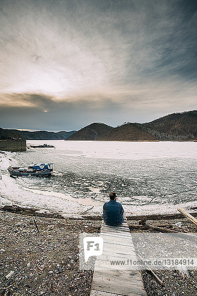 Russland  Amur-Oblast  Rückenansicht eines Mannes  der auf der Strandpromenade sitzt und auf die Aussicht schaut