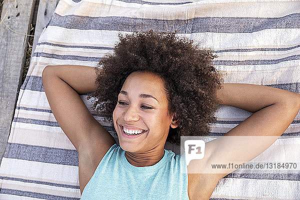 Porträt einer glücklichen Frau  die im Freien auf einer Decke liegt