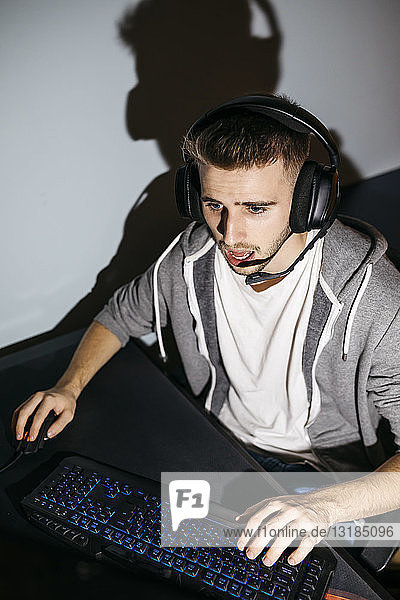 Junger Mann sitzt an seinem PC und spielt Computerspiele