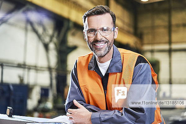 Portrait of smiling man in factory wearing protective glasses